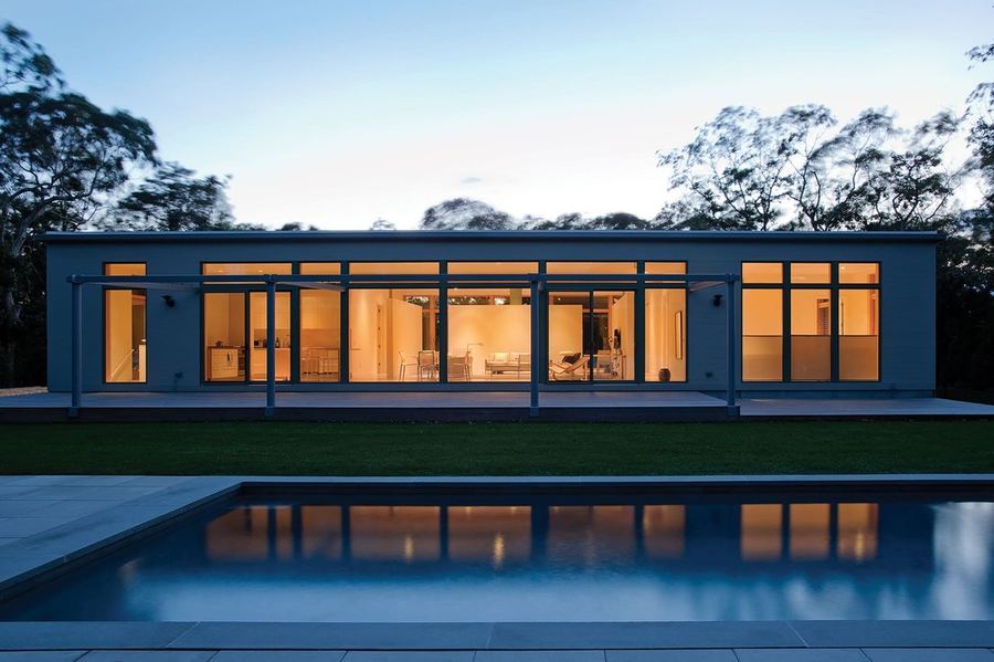 Modern Long Island home at dusk with pool